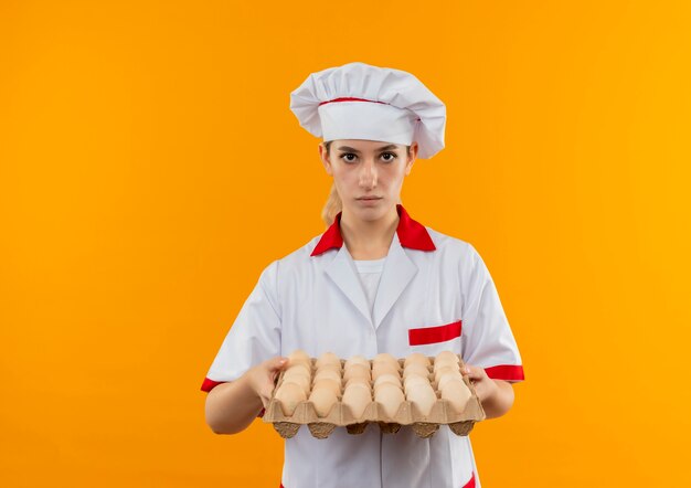 Piuttosto giovane cuoco in uniforme chef azienda cartone di uova