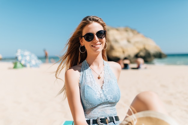 Piuttosto giovane donna seduta sulla sabbia sulla spiaggia