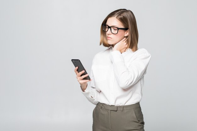 Piuttosto giovane imprenditrice guardando nello schermo del telefono tenendo il collo di dolore isolato