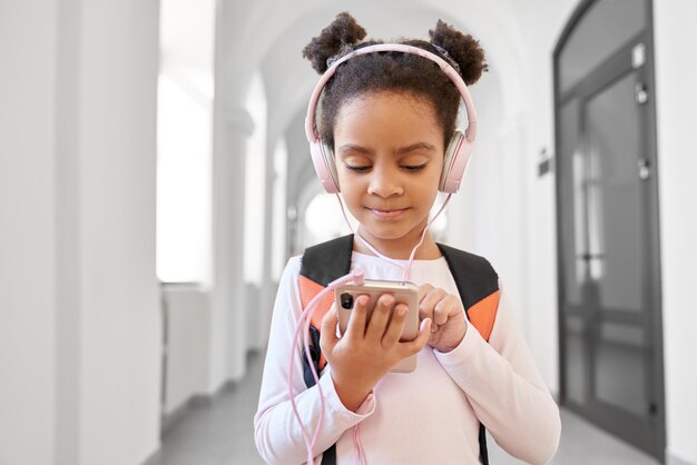 Piuttosto piccola scuola africana ragazza che indossa grandi cuffie