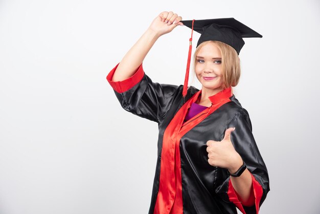 Piuttosto studente in abito che fa i pollici in su su sfondo bianco. Foto di alta qualità