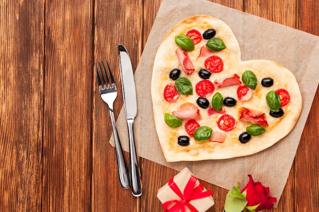 Pizza a forma di cuore vista dall'alto con stoviglie