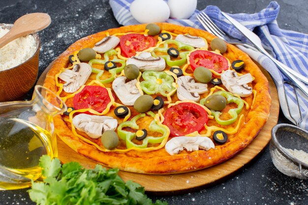 Pizza ai funghi vista frontale con pomodori rossi peperoni olive e funghi tutti affettati all'interno con uova su oscurità