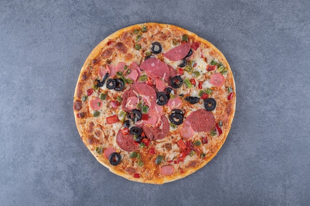 Pizza ai peperoni appena sfornata su sfondo grigio.