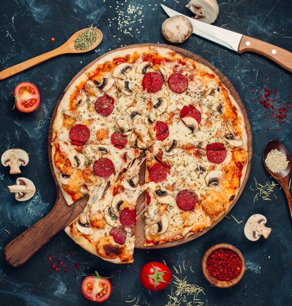 Pizza ai peperoni con funghi sul tavolo