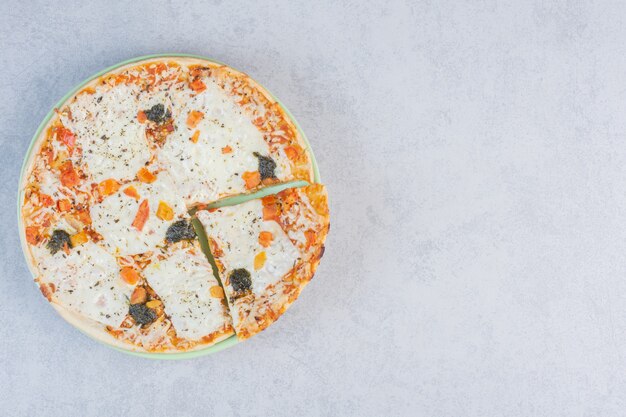 Pizza ai quattro formaggi bianca con parmigiano fuso su fondo grigio.