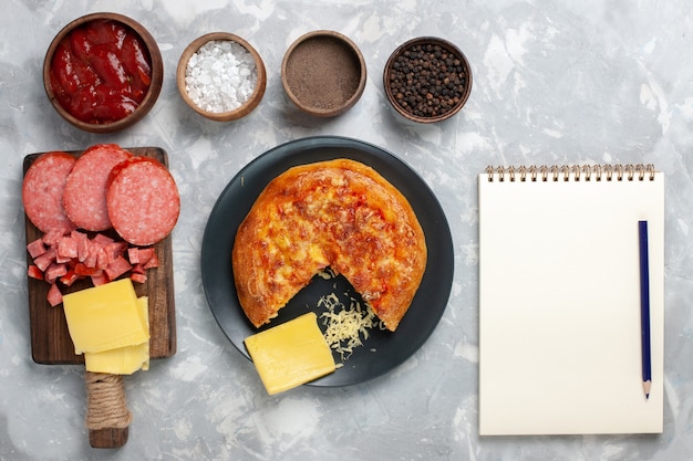 Pizza al formaggio vista dall'alto con diversi condimenti sulla scrivania bianca
