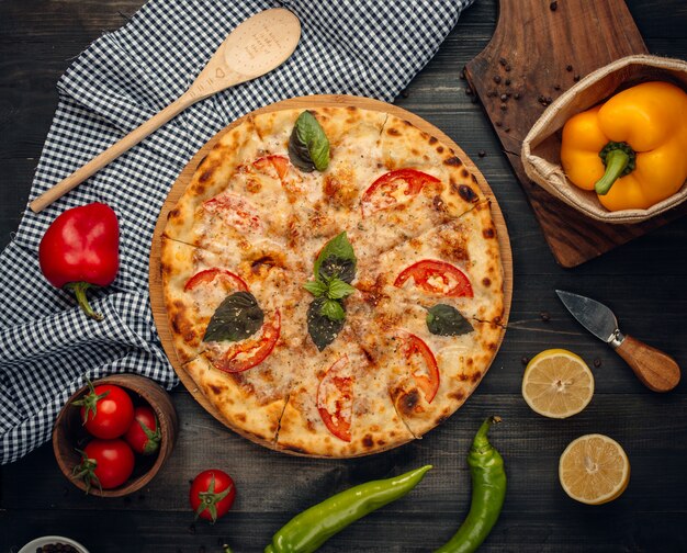 Pizza con fette di pomodoro e basilico verde.