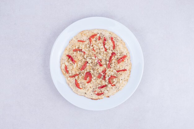 Pizza con peperoni sul piatto di legno su bianco