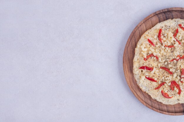 Pizza con peperoni sul piatto di legno sulla superficie bianca