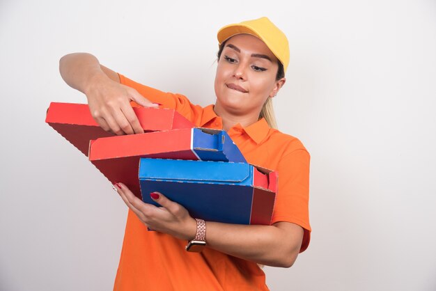 Pizza consegna donna che fissa le scatole per pizza su sfondo bianco.