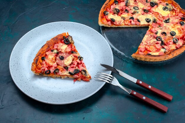 Pizza deliziosa cotta a metà vista con olive, salsicce e formaggio sulla scrivania blu.