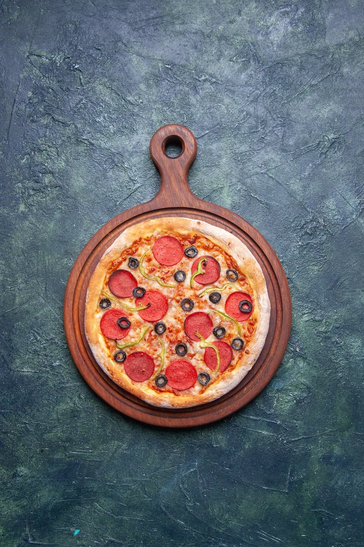 Foto gratuito pizza deliziosa su tagliere di legno su superficie blu scuro con spazio libero