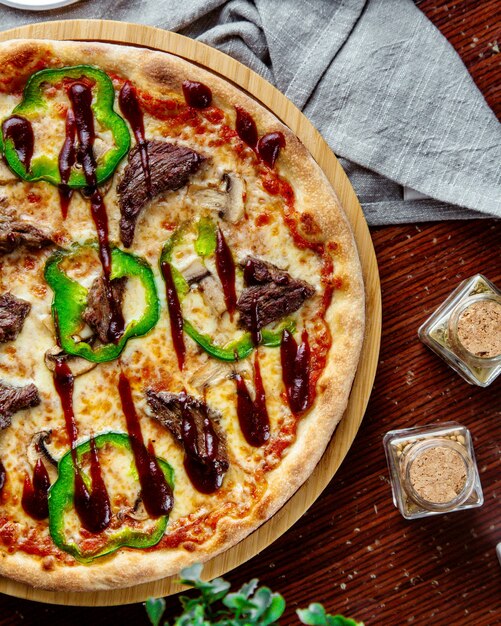 Pizza della carne di vista superiore con peperone dolce e salsa barbecue su un vassoio