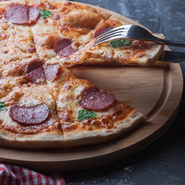 Pizza della salsiccia di vista laterale con le pentole a bordo della forcella e del tovagliolo