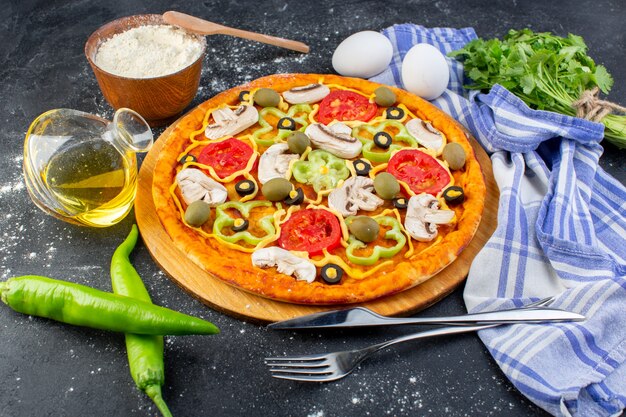 Pizza di funghi piccanti vista frontale con pomodori rossi peperoni olive e funghi tutti affettati all'interno con uova su grigio