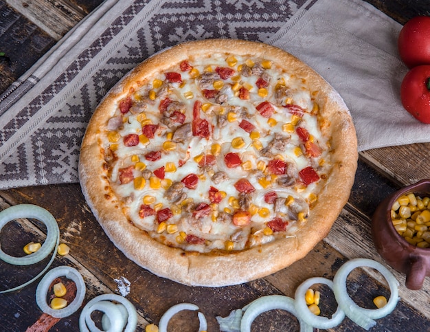 Pizza di pollo con pomodori, cipolle e salsa ranch sul tavolo di legno