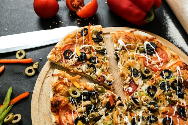 Pizza di pollo vista dall'alto con pomodori peperoni e olive su un vassoio