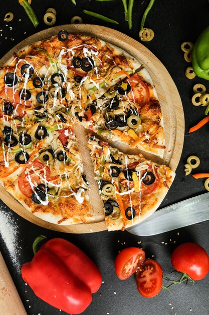 Pizza di pollo vista dall'alto con pomodori peperoni e olive su un vassoio