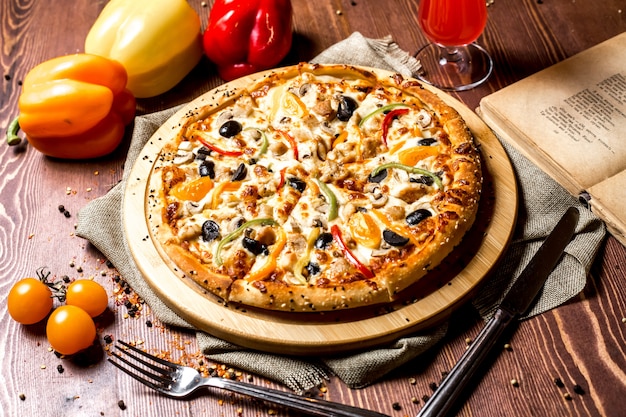 Pizza di pollo vista frontale con peperone rosso e giallo con pomodorini gialli