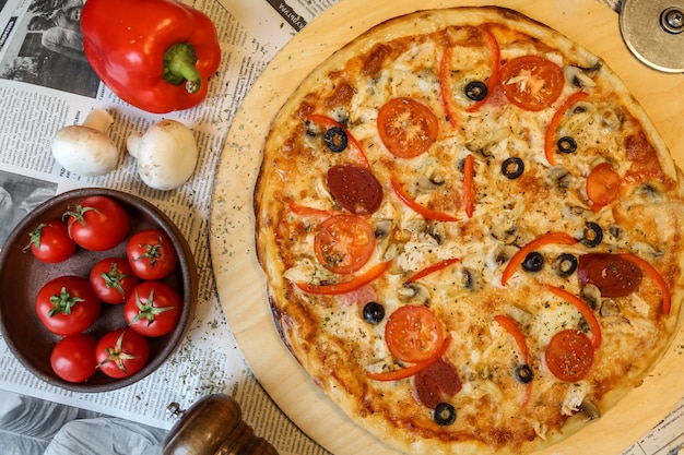 Pizza di salame vista dall'alto su un vassoio con funghi e pomodori con peperone bulgaro