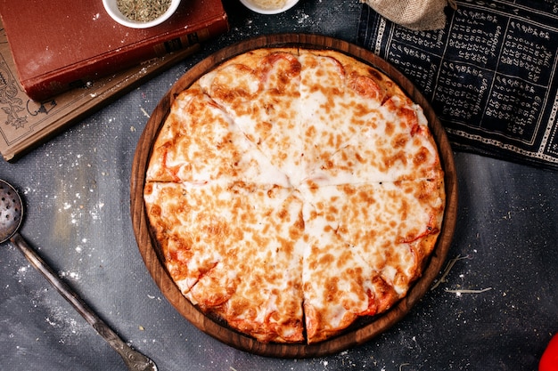 Pizza di vista frontale con formaggio sullo scrittorio di legno rotondo marrone e sulla superficie scura