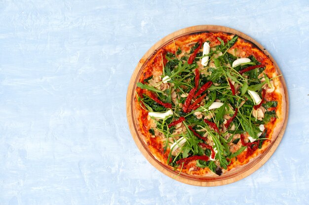 Pizza fresca con erbe e pomodori secchi sul tavolo grigio