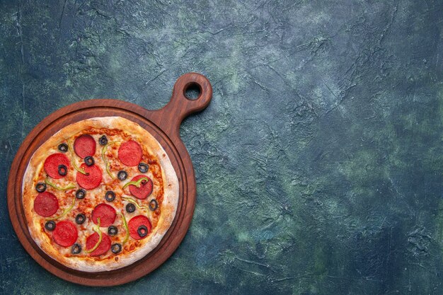Pizza gustosa su tagliere di legno sul lato destro su superficie blu scuro con spazio libero