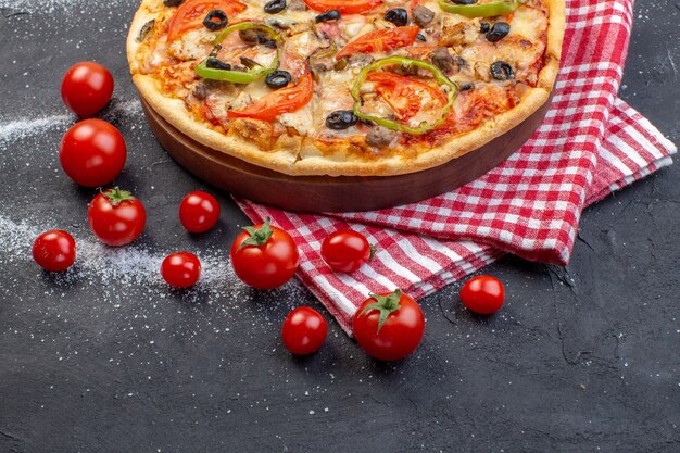 Pizza gustosa vista frontale con pomodori rossi su superficie scura