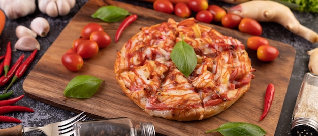 Pizza in un vassoio di legno con pomodori Peperoncino e basilico.