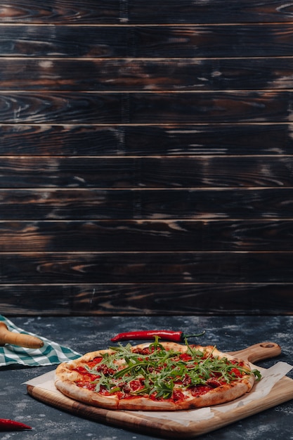 Pizza napoletana appetitosa e piccante a bordo con pomodorini e peperoncino, spazio libero per il testo