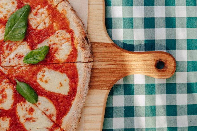 Pizza napoletana con prosciutto, formaggio, rucola, basilico, pomodori cosparsi di formaggio su una tavola di legno.