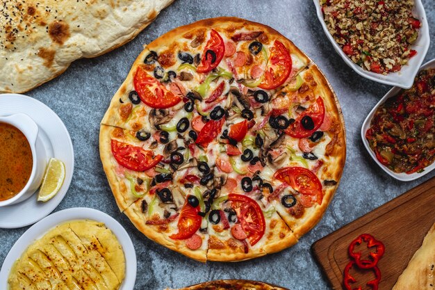 Pizza salsicce vista dall'alto con pomodoro peperone e formaggio olive nere sul tavolo