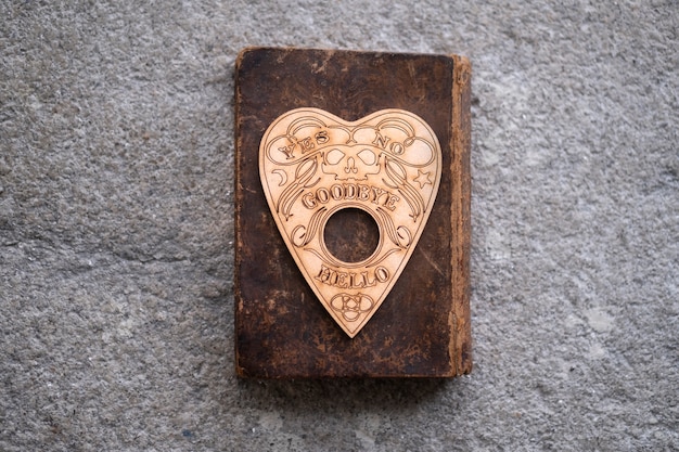 Planchette della tavola Ouija sulla vista dall'alto del vecchio libro