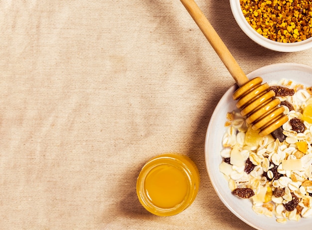 Polline d'api; barattolo di miele e avena sana sul panno di iuta