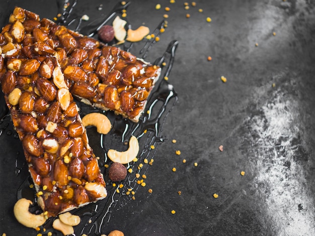 Polline d&#39;api e barrette di cereali frutta secca su marmo nero texture di sfondo