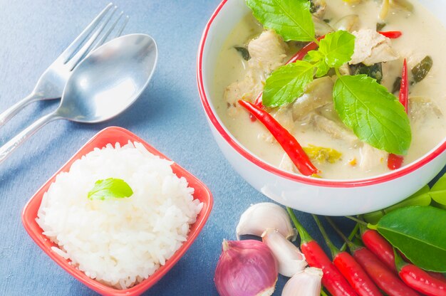 Pollo al curry verde con ingrediente piccante crudo e riso con cucchiaio e forchetta