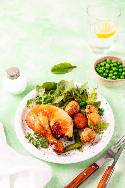 Pollo al forno con patate e insalata su uno sfondo verde