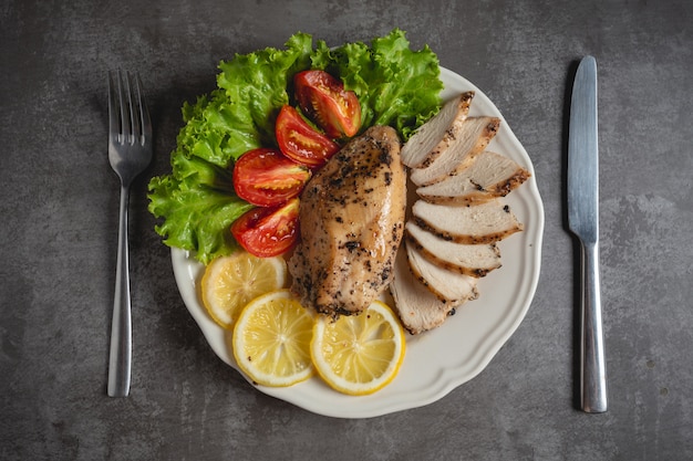 Pollo alla griglia su un piatto bianco.