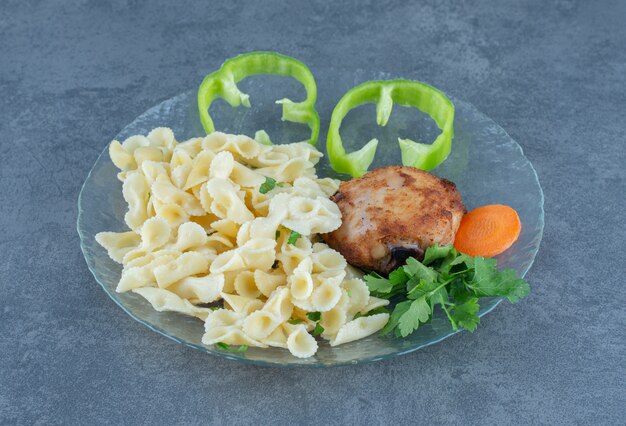 Pollo arrosto e pasta saporita sulla lastra di vetro.