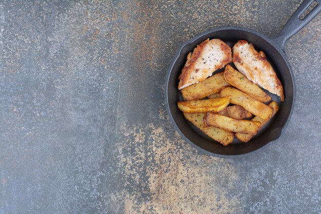 Pollo arrosto e patate in padella nera. Foto di alta qualità