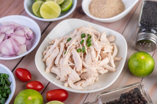 Pollo bollito tagliato a pezzi in un piatto bianco su un tavolo di legno.