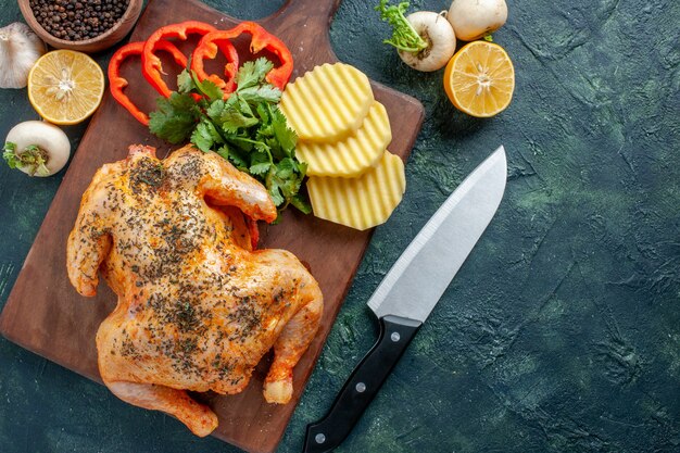 Pollo cotto vista dall'alto condito con patate sulla superficie scura