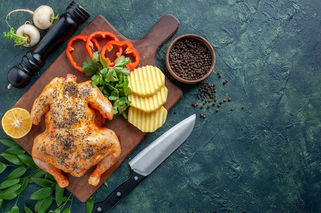 Pollo cotto vista dall'alto condito con patate sulla superficie scura