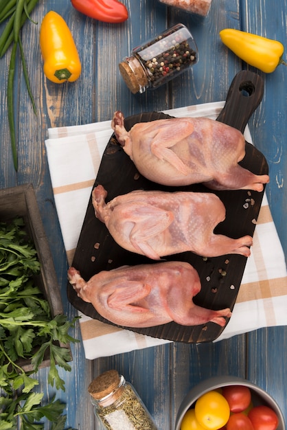 Pollo crudo di disposizione piana sul bordo di legno con i peperoni