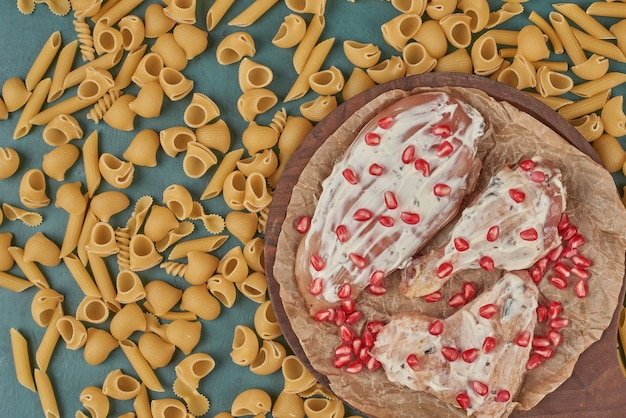 Pollo crudo su una tavola di legno con pasta.