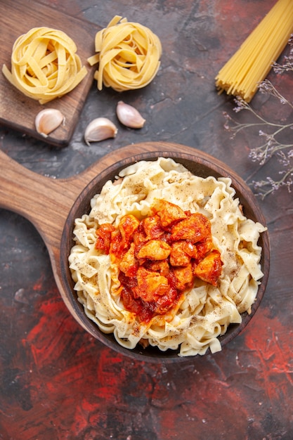 Pollo di vista superiore con il piatto di pasta della pasta su una pasta scura del piatto della pasta di superficie scura