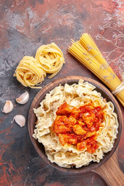 Pollo di vista superiore con il piatto di pasta della pasta sulla pasta scura del piatto di pasta di superficie scura