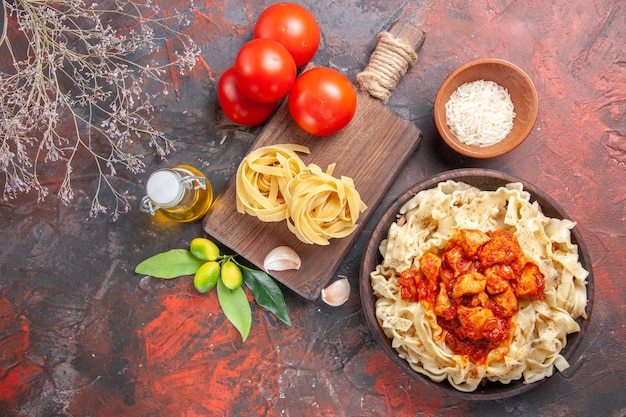 Pollo di vista superiore con piatto di pasta della pasta con i pomodori sulla farina della pasta della pasta del pavimento scuro