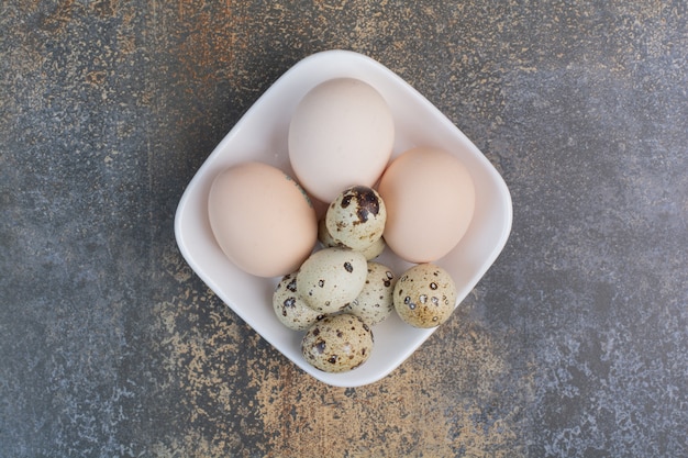 Pollo e uova di quaglia sulla ciotola bianca